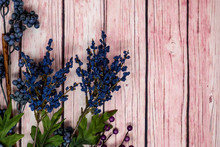 Blue And Purple Floral Arrangement Scene With Blueberries Over A Pink Wooden Background. Concept For Fall Or Summer Headers.