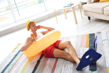 Sticker - Shirtless man with inflatable ring and bottle of drink wearing flippers on floor at home