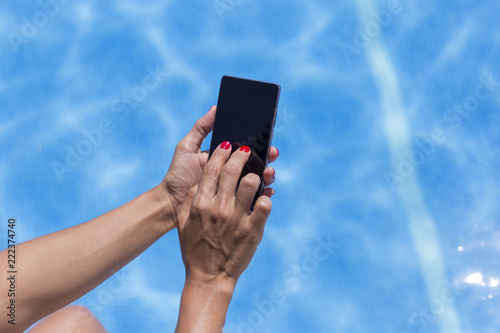 Fotografie, Obraz woman hands using mobile phone at the pool