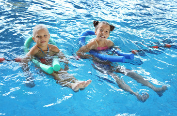 Wall Mural - Little girls with swimming noodles in indoor pool