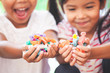 © pingpao - Two asian child girls holding sweet candies in thier hands and share to each other