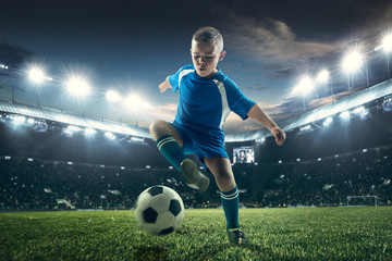 Wall Mural - Young boy with soccer ball doing flying kick at stadium. football soccer players in motion on green grass background. Fit jumping boy in action, jump, movement at game. Collage