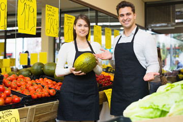 Wall Mural - Positive young beautiful seller holding musk-melon in market