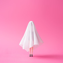 Girl In Ghost Costume Against Pastel Pink Background. Halloween Party Minimal Concept.