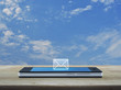 email flat icon on modern smart mobile phone screen on wooden table over blue sky with white clouds, Business communication online concept