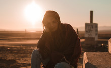 Front View Of Young Woman Posing And Looking At Camera On A Desert In A Sunset
