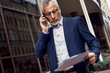 © Friends Stock - Senior businessman is discussing on the phone a contract outdoors near office