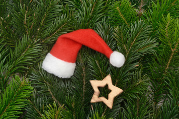 santa hat and wooden star  lying on fir branches