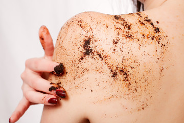 beauty, people and healthy skin concept - Brunette cleanses skin coffee scrub white background Beauty Portrait. Beautiful Spa Woman Touching her Face. Perfect Fresh Skin Youth and Skin Care Concept