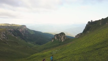 Wall Mural - group of tourist people hiking in green mountain aerial landscape