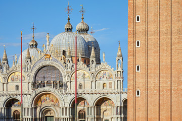 San Marco basilica facade and red bricks bell tower detail in Venice, blue sky in a sunny day in Italy