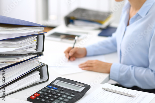 Cuadros en Lienzo Calculator and binders with papers are waiting to be processed by business woman or bookkeeper back in blur