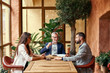 © Friends Stock - Professional team. Positive nice smart colleagues sitting together in the cafe and discussing their project while working in team