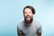 © golubovy - happiness enjoyment and laugh. man with a wide grin. portrait of a young bearded hipster guy on blue background. emotion facial expression. feelings and people reaction.