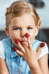 Wall Mural - adorable child eating raspberries and looking at camera