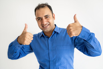 Happy Indian man showing both thumbs up and looking at camera. Handsome guy advertising something. Promotion concept. Isolated front view on white background.