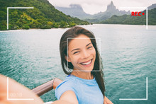 Travel tourist woman vlogging doing video vlog online during Tahiti luxury cruise vacation. Asian girl talking online doing video blog recording in Bora Bora island landscape.