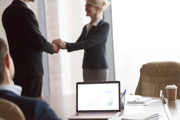 Wall Mural - Multiracial businesspeople at meeting. Director welcomes new colleague, hr. Acquaintance and greeting, reward, focus on computer on desk. Client and executor shaking hand after successful deal concept