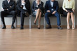 Close up businesspeople legs sitting in chair in queue wait job interview. Some of candidates sleeping, stressed tired and exhausted. Competition company position. Human resources, recruiting concept