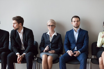 Sticker - Group of serious young and middle aged candidates professionals business people sitting in chairs in queue waiting job interview, for one position at company. Human resources, hr, recruitment concept