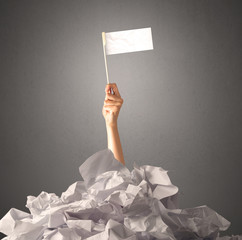 Wall Mural - Female hand emerging from crumpled paper pile holding a white blank flag 