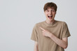 © timtimphoto - Portrait of happy surprised young man student with metal braces on teeth and opened mouth in beige t shirt looks amazed and points to the side isolated over white background