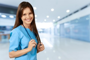 Wall Mural - Attractive young female doctor on blurred hospital background