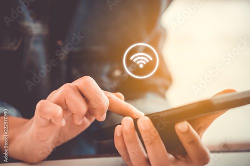 Fotografía Woman hand using smartphone with wifi icon in cafe shop background