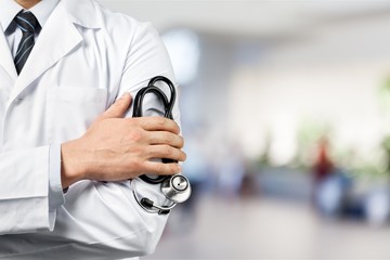 Male doctor with stethoscope on blurred hospital background