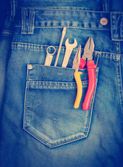 Several tools on a denim workers pocket toned with a retro vintage instagram filter effect app or action.