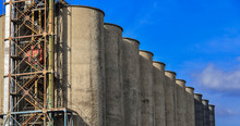 Line Of Seven Cement Grain Storage Silos Against Blue Sky