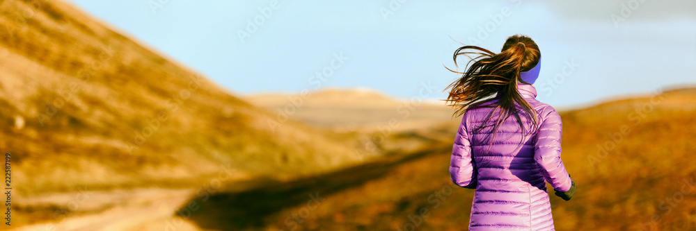 Running woman in autumn foliage background. Athlete runner on trail run outdoors panoramic banner. Active person jogging in down jacket from behind. - obrazy, fototapety, plakaty 