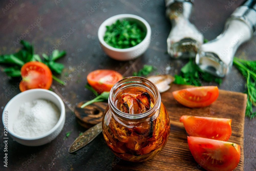 Appetizer, delicacy: preparation of dried tomatoes in a jar with spices, on a dark background. - obrazy, fototapety, plakaty 
