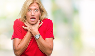 Middle age blonde woman over isolated background shouting and suffocate because painful strangle. Health problem. Asphyxiate and suicide concept.