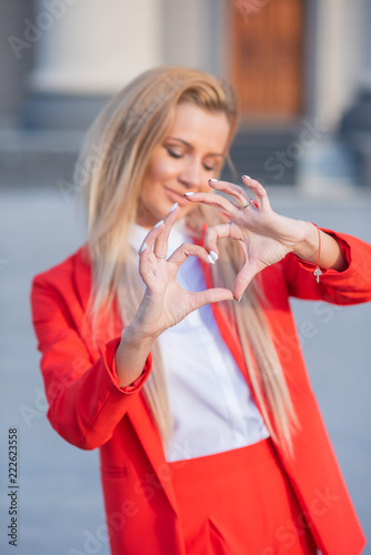 Fotografia Beautiful blonde in a red jacket and pants on a building background with columns