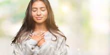 Young Beautiful Arab Woman Wearing Winter Sweater Over Isolated Background Smiling With Hands On Chest With Closed Eyes And Grateful Gesture On Face. Health Concept.