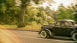 Old classic car driving fast on a vintage car rally blurred background and the car is out of focus