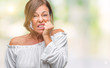 © Krakenimages.com - Middle age senior hispanic woman over isolated background looking stressed and nervous with hands on mouth biting nails. Anxiety problem.