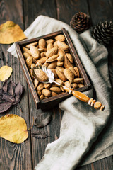 Wall Mural - Almonds, shell nuts in a box on a wooden background, autumn still life