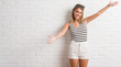 © Krakenimages.com - Young beautiful blonde woman over white brick wall looking at the camera smiling with open arms for hug. Cheerful expression embracing happiness.