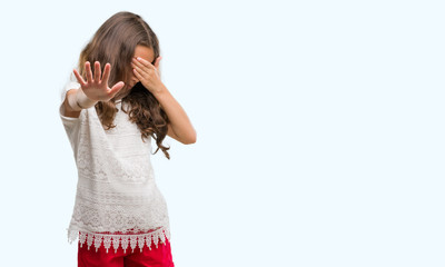 Sticker - Brunette hispanic girl covering eyes with hands and doing stop gesture with sad and fear expression. Embarrassed and negative concept.