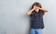 © Krakenimages.com - Young hispanic kid over grunge grey wall suffering from headache desperate and stressed because pain and migraine. Hands on head.
