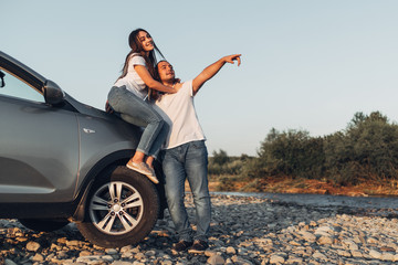 Wall Mural - Happy Couple on Roadtrip into the Sunset in SUV Car