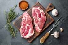 Raw Pork Steaks With Seasoning On Wooden Board. Gray Slate Background