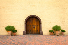 Old California Mission Church Door With Red Brick Floor And Potted Plants