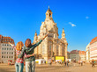 Two happy women hugging and looking at the main attraction of Dresden - Frauenkirche