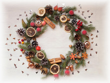 Christmas And  New Year Background / A Christmas Wreath From Spruce Twigs,pine Cones,cinnamon Sticks,dry Lemon,berries,balls And Candies