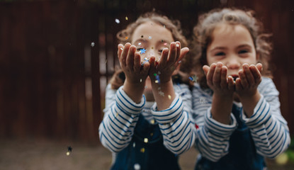 Twin sisters enjoying blowing glitter