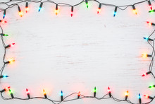 Christmas Lights Bulb Frame Decoration On White Wood. Merry Christmas And New Year Holiday Background. Top View