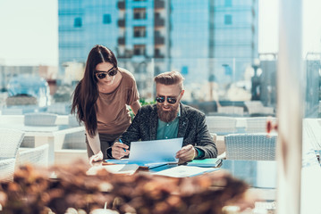 Aufkleber - Portrait of orderly female and outgoing unshaven businessman discussing project while locating at table outdoor. Colleagues during labor concept